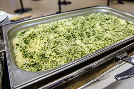 Photo for Rice with greens, a vegetarian dish in a heated container. catering buffet for events in hotel restaurant - food and drink - Royalty Free Image