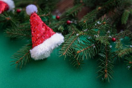 Photo for Christmas decoration with fir branches and Santa Claus hat on a green background - Royalty Free Image