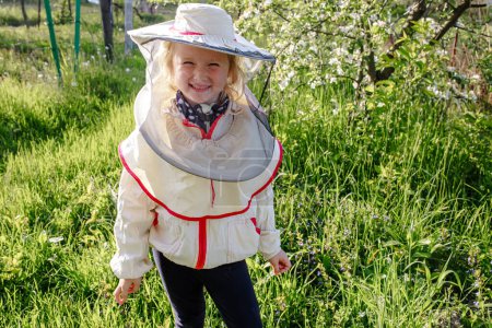 Téléchargez les photos : Portrait d'une petite fille en costume d'apiculteur. Les enfants apprennent à prendre soin des abeilles. - en image libre de droit