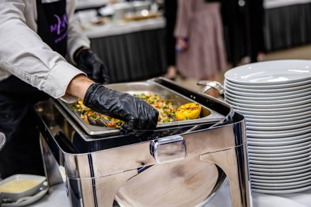 Téléchargez les photos : Chef dans la cuisine de l'hôtel préparant la nourriture, service de restauration et concept de personnes. restauration buffet à l'intérieur dans un restaurant de luxe avec saumon fruits et légumes colorés - en image libre de droit