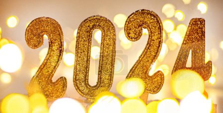Photo for 2024 New Year Background. Text by candles with christmas lights and bokeh on gold background. - Royalty Free Image