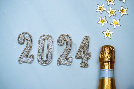 Téléchargez les photos : Nouvel An 2024. Fond festif avec une bouteille de vin mousseux et des numéros dorés sur fond bleu.. - en image libre de droit