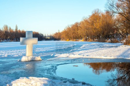Téléchargez les photos : Trou de glace creux gelé sert de lieu pour l'immersion des croyants dans un rite religieux, marquant l'Épiphanie avec des eaux glacées et une croix imposante. - en image libre de droit