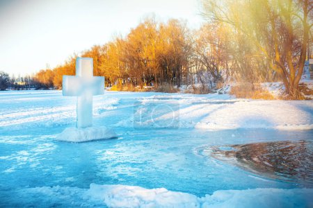 Téléchargez les photos : Symbole chrétien de la croix, faite d'un bloc de glace sur la glace près d'un trou de glace dans un lac gelé pendant la fête orthodoxe de l'Épiphanie - en image libre de droit