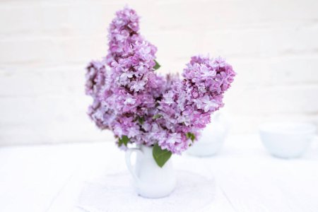 Téléchargez les photos : Lot de fleurs lilas violettes sur table blanche en vase, détails déco. Bouquet de fleurs printanières à la maison. - en image libre de droit