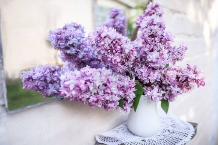 Téléchargez les photos : Bouquet de lilas violets sur une étagère près d'un miroir vintage. Reflet des fleurs et de la cour dans un vieux miroir. Décor de maison avec des fleurs de printemps.. - en image libre de droit