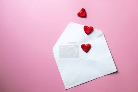 Photo for Valentine's Day background. Blank white envelope with red hearts on pink background. - Royalty Free Image