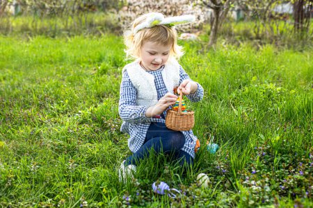 Photo for Cute little girls hunting for eggs in the park. Easter tradition - Royalty Free Image