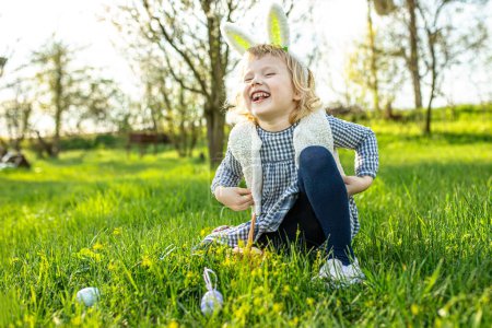 Foto de Regocijándose en la fiesta de Pascua y esperando a buscar huevos de Pascua en el parque entre la hierba. Caza de huevos - Imagen libre de derechos