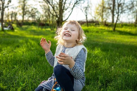 Photo for Easter Family traditions. Happy little girl wearing bunny ears and running on green grass in garden celebrating Easter egg hunt in garden - Royalty Free Image