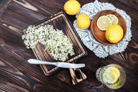 Téléchargez les photos : Broyage citron et sureau noir sur une planche à découper pour faire une boisson à base de plantes ou un médicament pour guérir à la maison du sirop de fleurs de sureau. - en image libre de droit