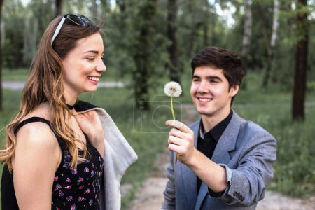 Photo for Portrait of young couple in love blowing dandelion in the park. concept of quitting smoking. - Royalty Free Image
