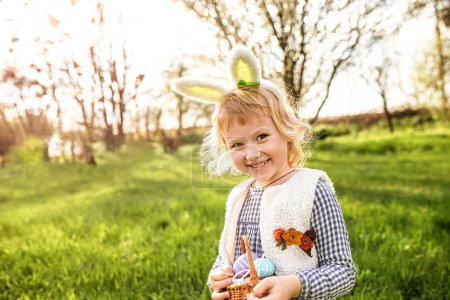 Téléchargez les photos : Petite fille tient un panier d'œufs de Pâques. Funny fille recueilli oeufs.. - en image libre de droit