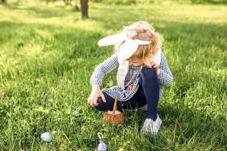 Foto de Niña Regocijándose en la fiesta de Pascua y esperando a buscar huevos de Pascua en el parque entre hierba verde. - Imagen libre de derechos