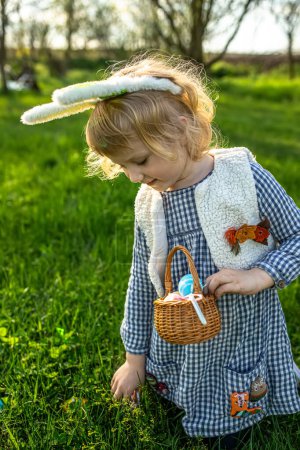 Téléchargez les photos : Petit aventurier en quête de Pâques. Enfant explorant le jardin, panier à la main, à la recherche d'œufs décorés. - en image libre de droit