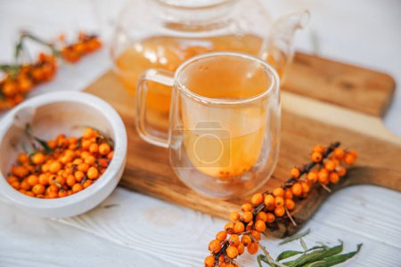 Foto de Copa de vidrio y tetera con té de espino cerval de mar, mezcla de sabores y beneficios para la salud, bebida sabrosa y medicinal. - Imagen libre de derechos