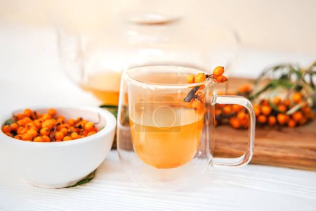 Foto de Copa de vidrio y tetera con té de espino cerval de mar, mezcla de sabores y beneficios para la salud, bebida sabrosa y medicinal. - Imagen libre de derechos
