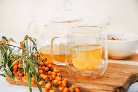 Téléchargez les photos : Coupe en verre et théière avec thé d'argousier, mélange de saveurs et de bienfaits pour la santé, boisson savoureuse et médicinale. - en image libre de droit