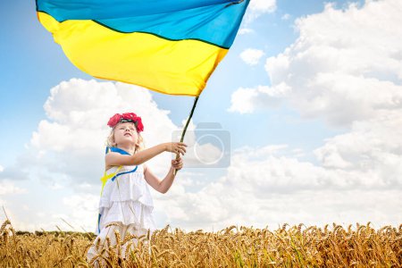 Photo for Ukraine's Independence Day. Little girl wrapped in flag of Ukraine. child holds blue-and-yellow flag on Flag Day and Constitution Day - Royalty Free Image