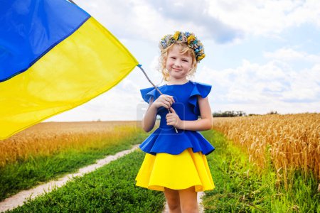 Foto de Chica patriótica mostrando bandera nacional ucraniana. niña con bandera de Ucrania. Bandera azul amarilla de Ucrania con escudo de armas en las manos del niño en el Día de la Independencia y el Día de la Bandera - Imagen libre de derechos