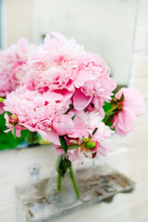 Téléchargez les photos : Bouquet de pivoines près du miroir sur étagère vintage dans le jardin au printemps - en image libre de droit