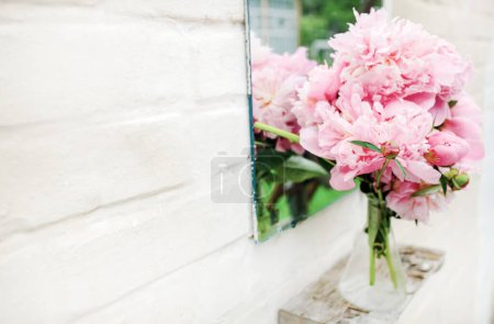Foto de Ramo de peonías cerca de espejo al aire libre cerca de la pared de ladrillo blanco. Copiar espacio - Imagen libre de derechos
