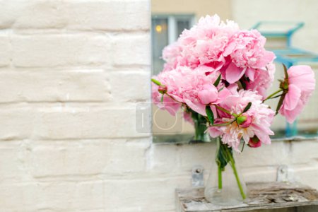 Photo for Bouquet of peonies near mirror outdoors near white brick wall. Copy space - Royalty Free Image