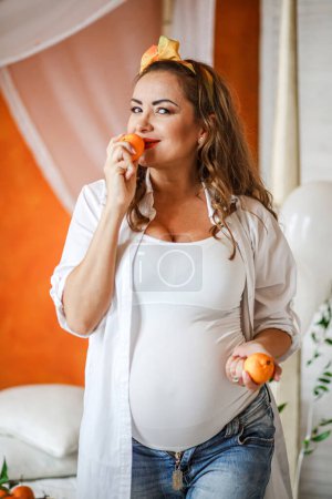 Téléchargez les photos : Femme enceinte avec des mandarines à la maison. Concept de saine alimentation.. - en image libre de droit