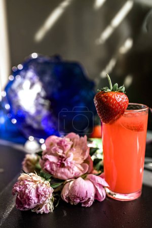 Photo for Strawberry cocktail with pink peonies on black background. freshness of a strawberry smoothie surrounded by peonies, a nutritious delight for any occasion. Symphony of flavors concept - Royalty Free Image