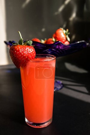 Téléchargez les photos : Jus de fraise dans un verre sur fond sombre. un verre de thé aux fraises. Concept de mélange Wellness - en image libre de droit