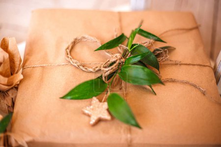 Téléchargez les photos : Le cadeau est décoré avec du papier kraf et des feuilles fraîches. Décor de cadeau rustique naturel concept - en image libre de droit