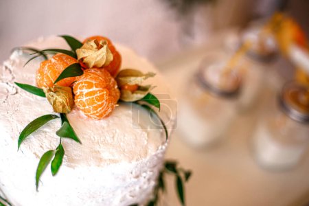 Le dessus du gâteau est décoré de feuilles d'orange fraîches et décoré de crème blanche lors d'une fête à thème. Concept de décoration de gâteaux sur le thème tropical