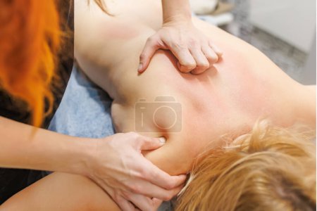 tranquilo santuario de spa, un masajista experto proporciona un masaje relajante en el cuello a una mujer joven. El cliente se entrega al lujoso tratamiento, sintiéndose rejuvenecido y renovado..