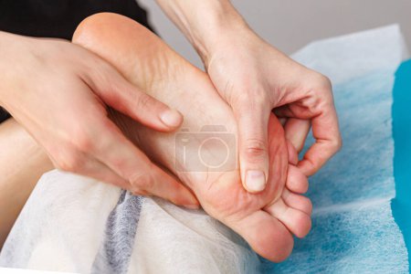 Téléchargez les photos : Avec un soin méticuleux, un masseur se concentre sur le massage du pied d'une jeune femme dans un salon moderne. - en image libre de droit