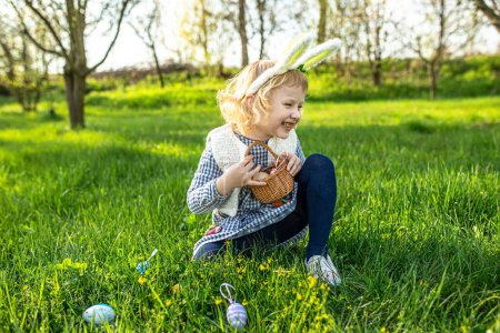 Emocionada niña se une a la caza de Pascua, recogiendo alegremente huevos en su cesta, creando recuerdos de risa y diversión.