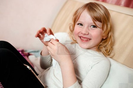 Foto de Retrato de niña con frío jugando con hisopos de algodón en casa - Imagen libre de derechos
