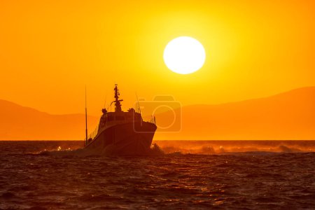 Photo for Coastguard boat sailing in the Aegean sea near Izmir city with the sunset sky and the Sun in the background - Royalty Free Image