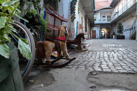 Téléchargez les photos : Plusieurs jouets, dont le vieux cheval à bascule dans la cour étroite de l'ancien quartier juif appelé Kazimierz à Cracovie en Pologne. - en image libre de droit