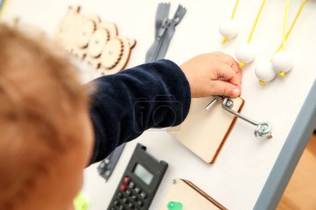 Photo for The small child plays with the activity board to get new experience, practice its skills and get an improvement during its growth. - Royalty Free Image