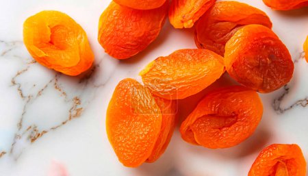 Téléchargez les photos : Les abricots secs comme les fruits secs sont éparpillés en tas sur un fond blanc - en image libre de droit