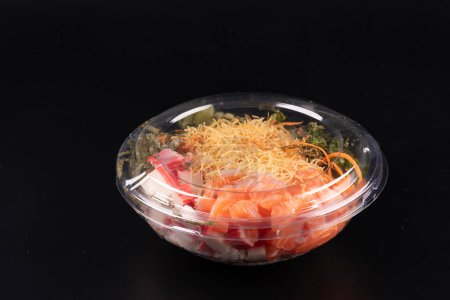 Foto de Tazón de comida japonesa oriental y kani aislado sobre fondo blanco salmón crudo cerrado con tapa de plástico fondo negro - Imagen libre de derechos