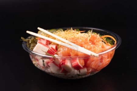 Foto de Tazón de comida japonesa oriental y kani aislado sobre fondo blanco salmón en ángulo crudo con un par de palillos fondo negro - Imagen libre de derechos