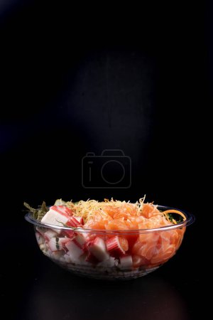 Foto de Tazón de comida japonesa oriental y kani aislado sobre fondo blanco salmón crudo en frente par de palillos fondo negro - Imagen libre de derechos