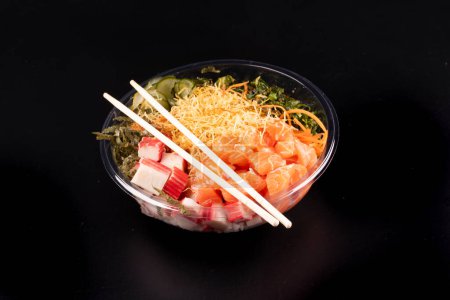 Foto de Oriental japonés comida poke y kani aislado en blanco fondo crudo angulado salmón con par de palillos negro fondo - Imagen libre de derechos