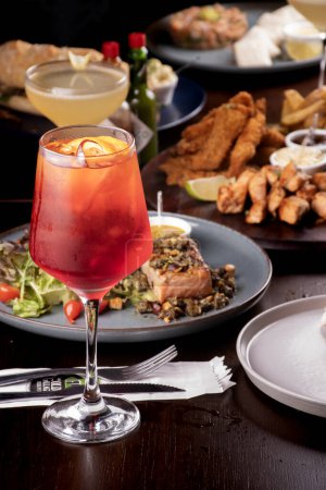 Téléchargez les photos : Table de banquet avec saumon et fruits de marque au restaurant et verre à cocktail rouge en focus aperol spritz - en image libre de droit