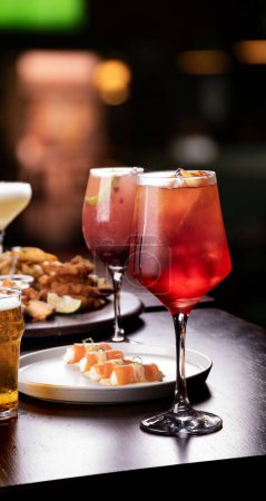 Téléchargez les photos : Table de banquet avec du saumon et des fruits de marque au restaurant et verre à cocktail rouge en focus bière spritz apéro - en image libre de droit