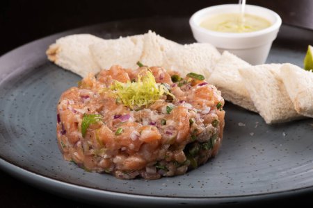 Téléchargez les photos : Tartare de saumon cru avec sauce et pain grillé au citron et gros plan - en image libre de droit