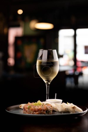 Téléchargez les photos : Tartare de saumon cru avec sauce grillée et citron associé au vin blanc restaurant flou - en image libre de droit