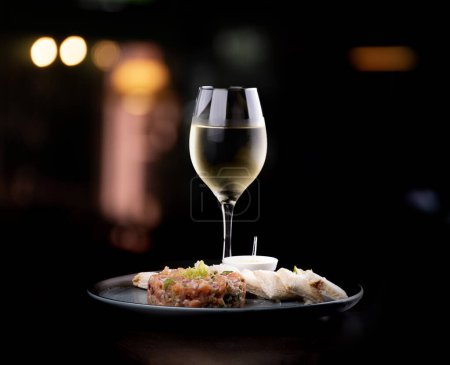 Téléchargez les photos : Tartare de saumon cru avec sauce grillée et citron associé au vin blanc - en image libre de droit