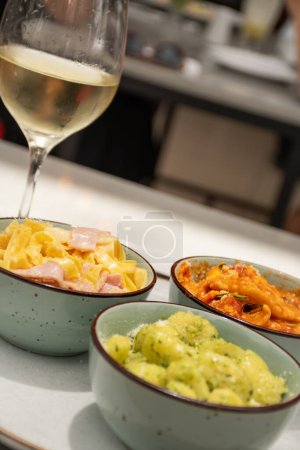 Téléchargez les photos : Assortiment avec différents plats de pâtes et verre de vin blanc gnocchi pesto tagliatelle et ravioli gros plan - en image libre de droit